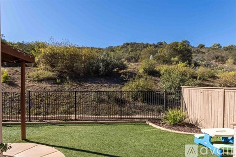 A backyard with a fence, a bench, and a picnic table.