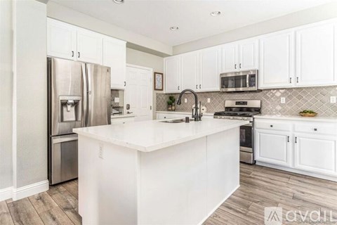A kitchen with white cabinets and a white island.