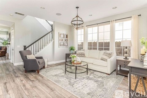 A living room with a grey sofa, a grey armchair, a glass coffee table and a wooden floor.