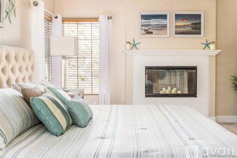 A bedroom with a large bed and a fireplace.