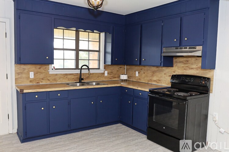 A kitchen with blue cabinets and a black stove.