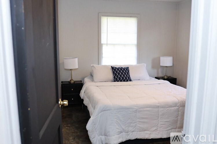A bedroom with a white bed and two lamps on either side of the bed.