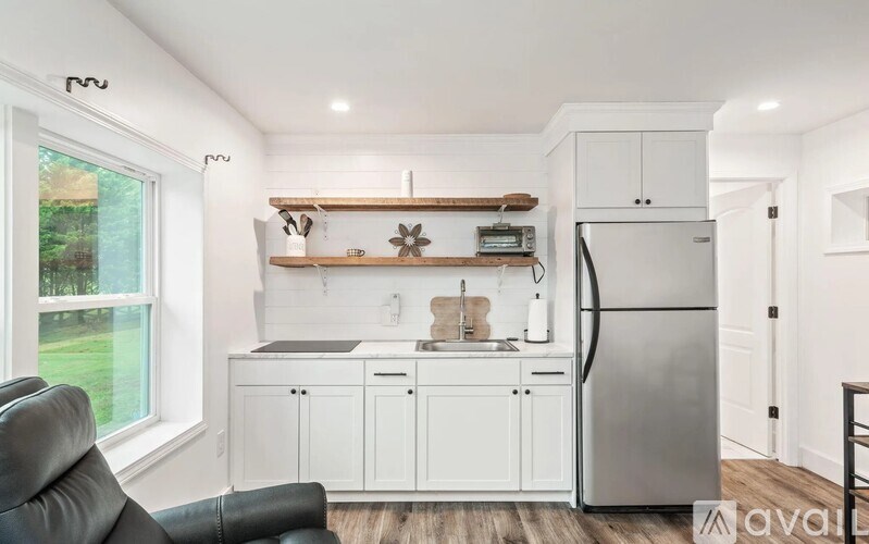 A kitchen with white cabinets and a wooden shelf above the sink.