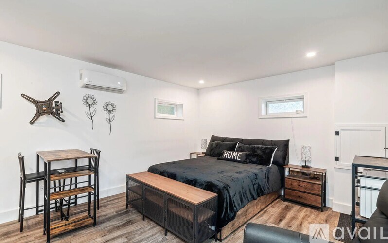 A bedroom with a black bed and a wooden chair.