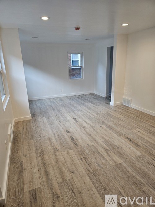 A spacious room with wooden flooring and a window.