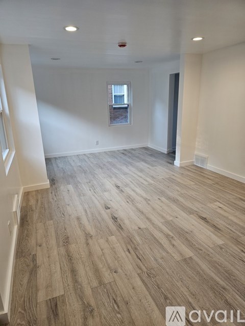 A spacious room with wooden flooring and a window.