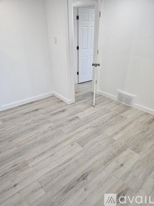 A room with a white door and a wooden floor.