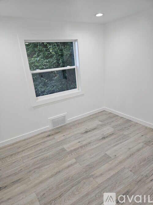 A room with a window and wooden flooring.
