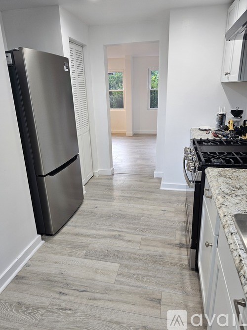 A kitchen with a black fridge and a wooden floor.