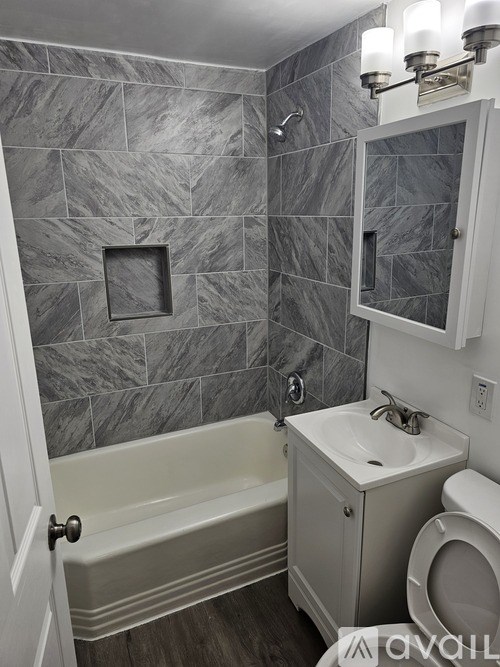 A bathroom with a grey tiled wall and a white toilet.