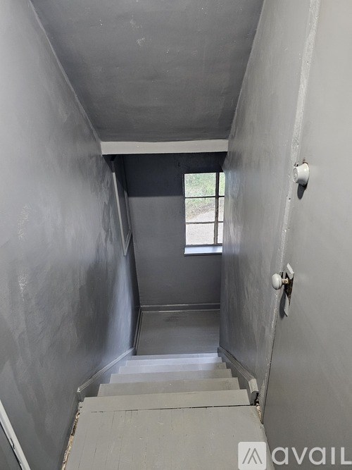 A long hallway with a window and a door at the end.