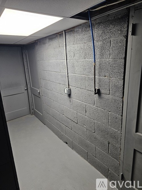 A long hallway with a brick wall and a door on the right.