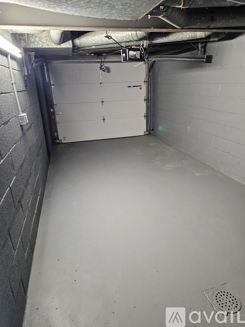 A white garage door is open in a dimly lit garage.