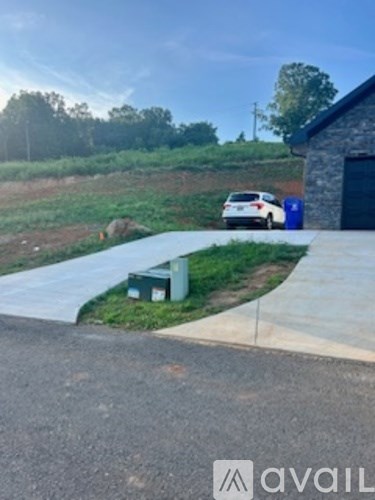 A white car is parked in front of a blue trash can.