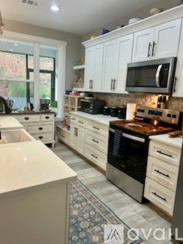 A kitchen with white cabinets and a stove top oven.