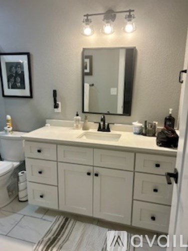 A bathroom with a white vanity and a white toilet.