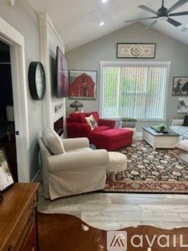 A living room with a red chair and a fan on the ceiling.