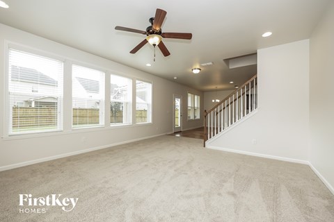 A spacious room with a fan and carpeted floor.