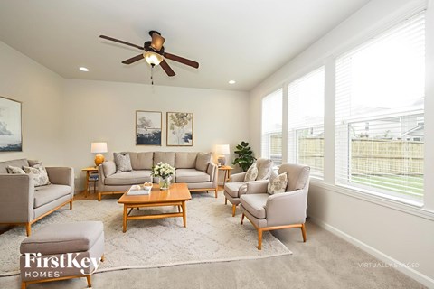A well-lit living room with a variety of seating options and a ceiling fan.