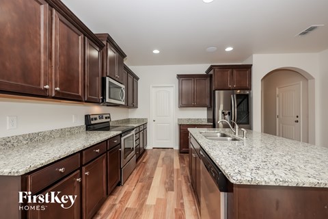 A kitchen with brown cabinets and a FirstKey Homes logo.