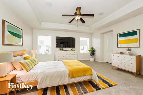 A bedroom with a bed, dresser, and ceiling fan.