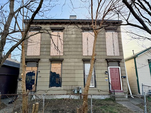 A house with boarded up windows and a red door.