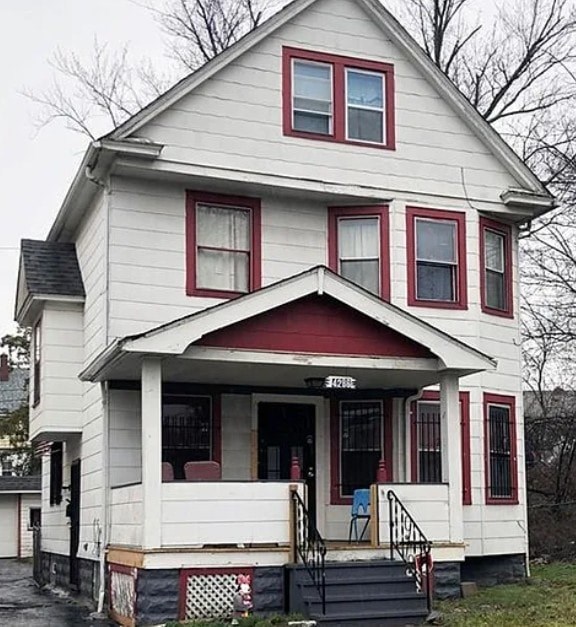 A white house with red trim and a red awning.