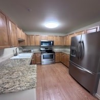 A kitchen with a refrigerator, oven, microwave, and sink.