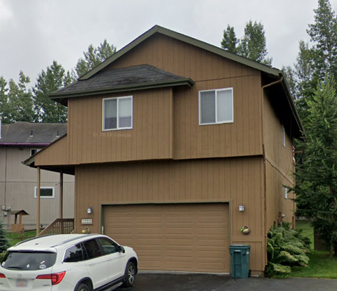 A brown house with a white car in front.