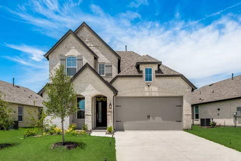 A large house with a garage door and a tree in front.