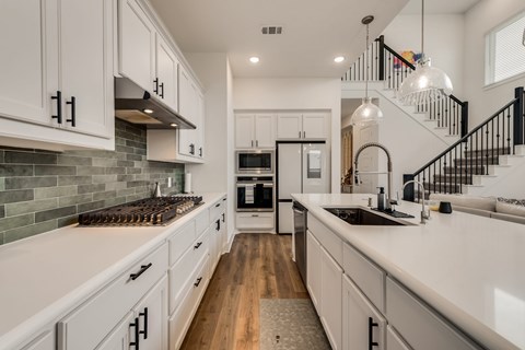 A modern kitchen with white cabinets and a wooden floor.