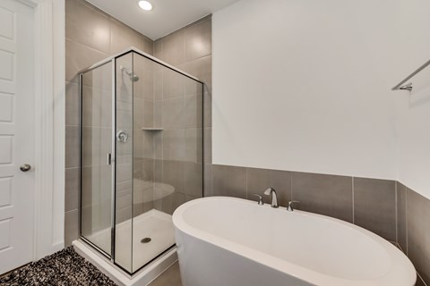 A white bathroom with a glass shower stall and a white bathtub.