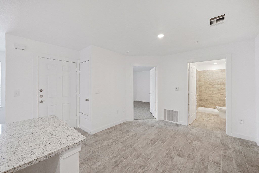 A spacious room with a marble countertop and light-colored wood flooring.
