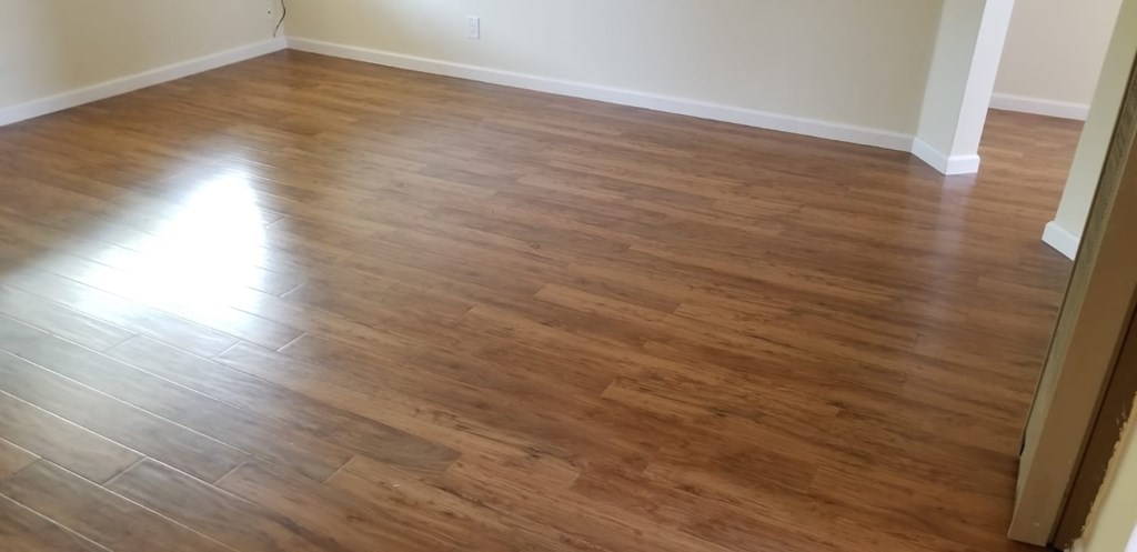 A room with wooden flooring and a white wall.
