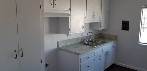 A kitchen with white cabinets and a marble countertop.