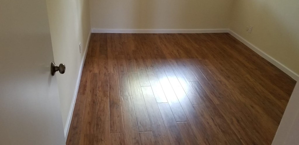 A room with a wooden floor and a door on the left.
