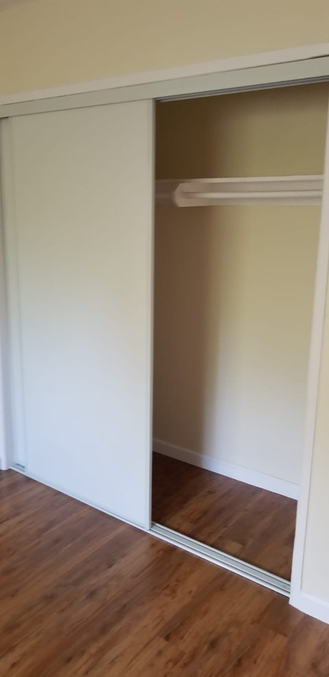 A white closet with a shelf and a mirror.
