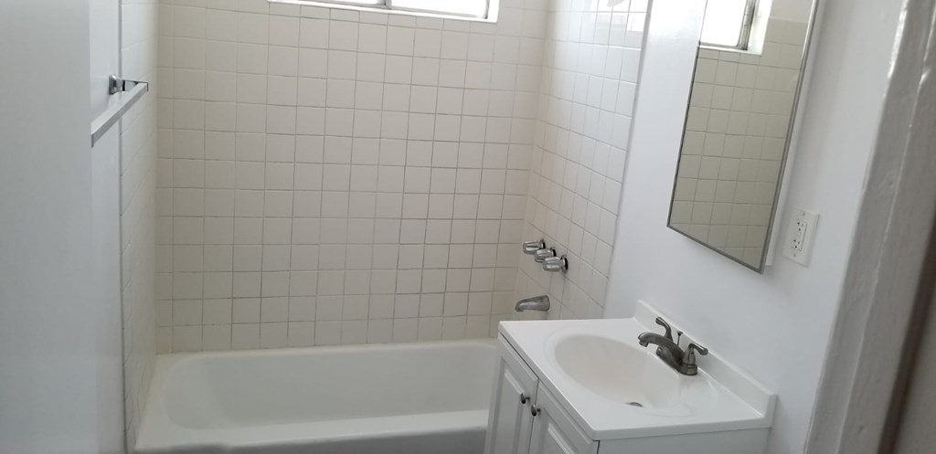 A white bathroom with a white tub and sink.