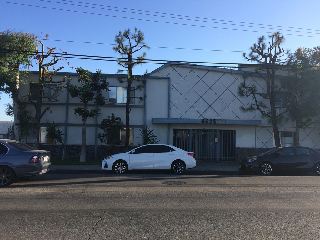 A white car is parked in front of a building with the number 432.