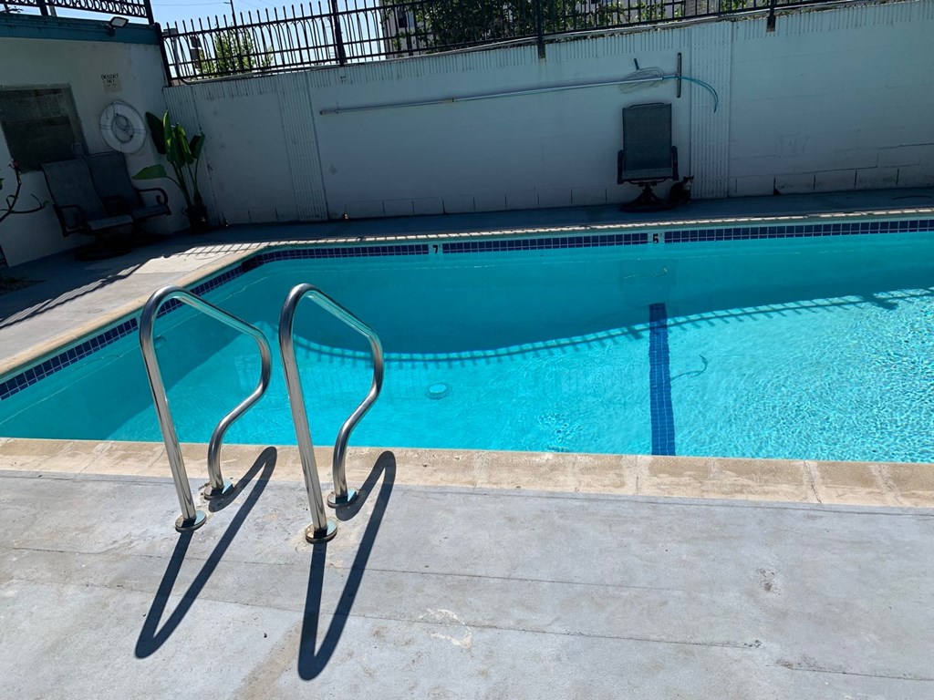 A pool with a diving board and a chair.
