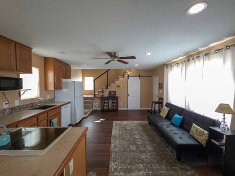 A kitchen with a refrigerator, sink, and a counter with a microwave on it.