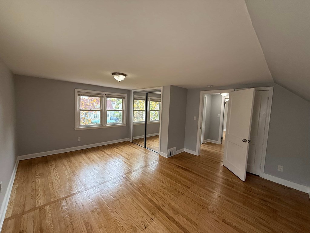 A room with wooden floors and a window with a view of trees.