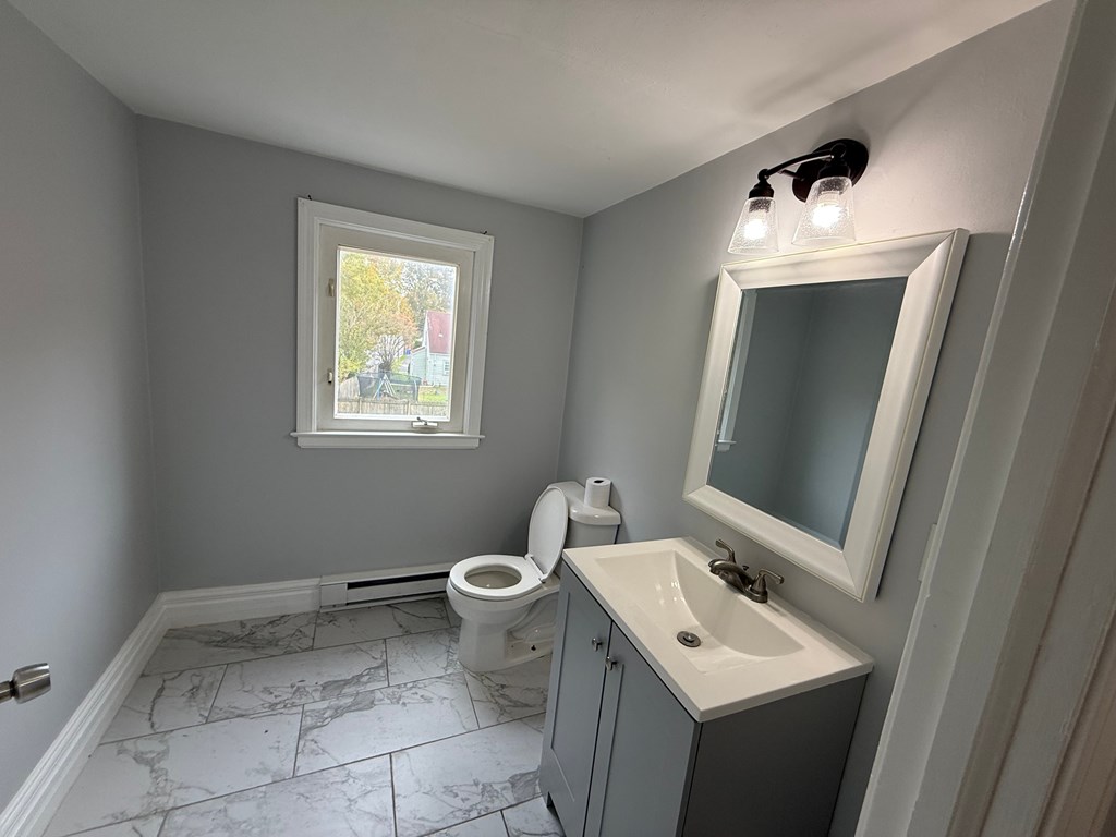 A bathroom with a toilet, sink, and mirror.