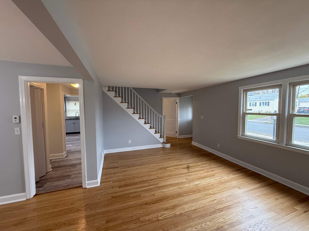 A room with wooden floors and a staircase leading to another room.