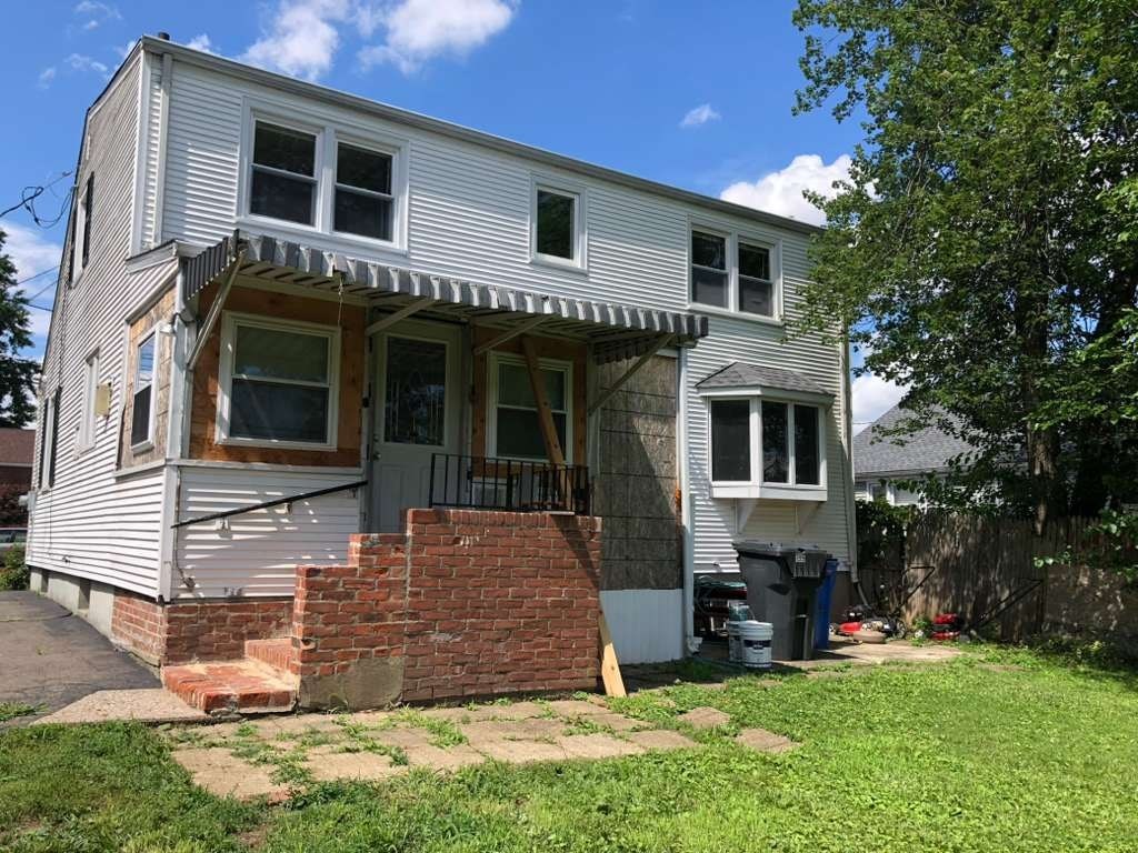 A house with a grey siding and a white roof is shown.