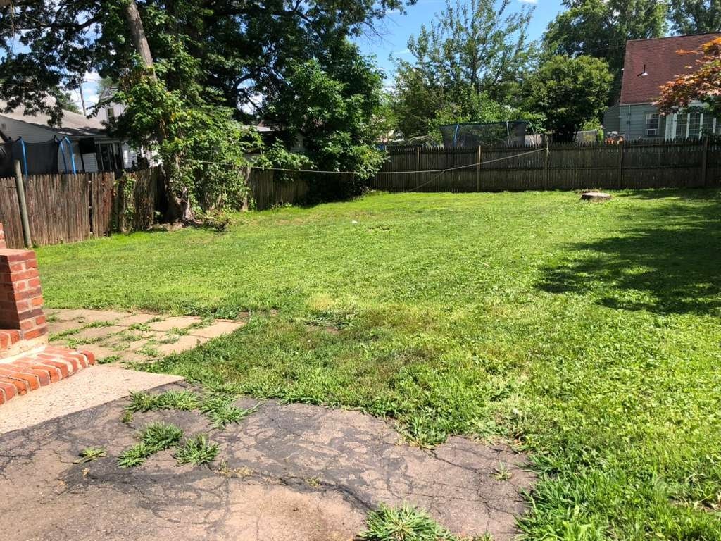 A backyard with a grassy area and a brick pathway.