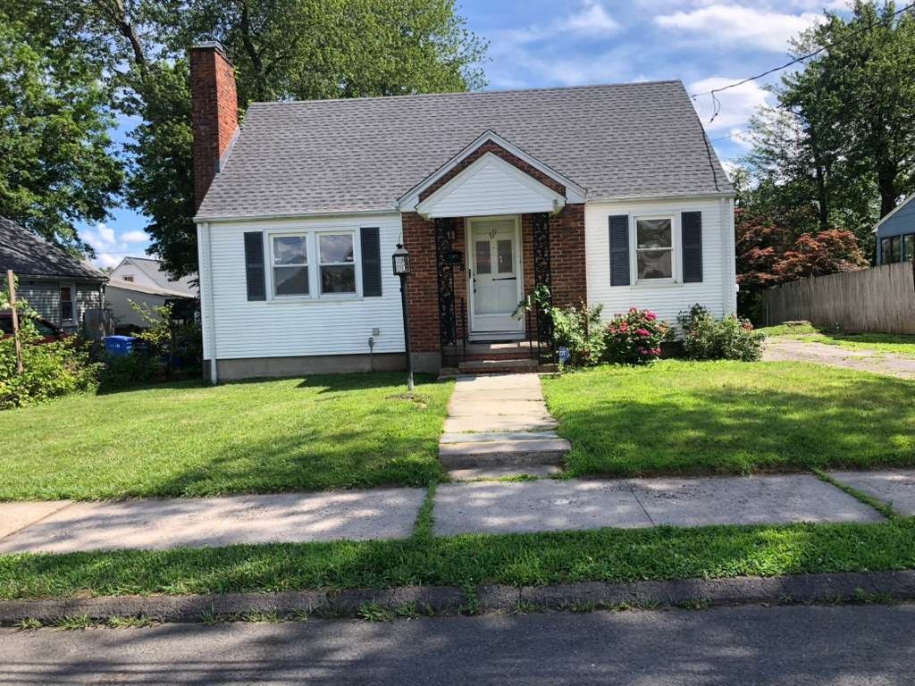A small white house with a brick chimney and a grey roof.
