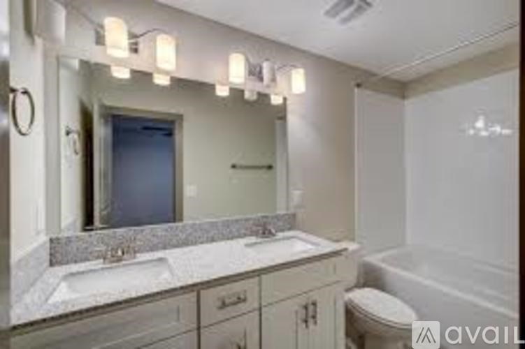 A bathroom with a large mirror, a sink, and a bathtub.