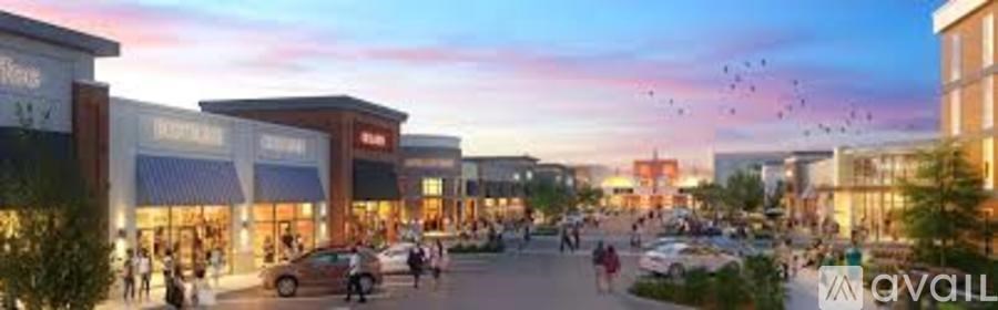 A busy shopping area with people walking and cars parked.