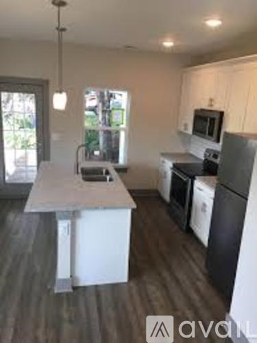 A kitchen with a black refrigerator and white cabinets.